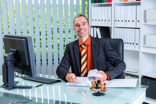 young business man at his desk looking friendly in to the camera