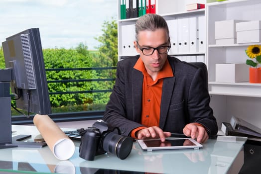 young reporter working in editorial office with tablet computer