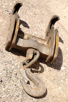 The close-up of a crane hook is placed on a gravel bed.
