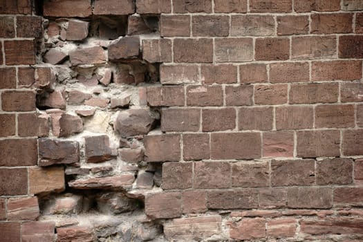 A wall of striking red stones with damage and holes.