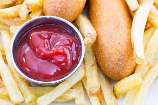 Close up of ketchup with fries and corn dogs