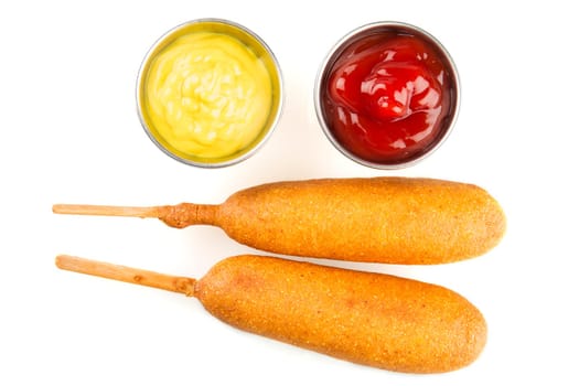 Two corndogs with mustard and ketchup on the side.  Isolated on a white background.