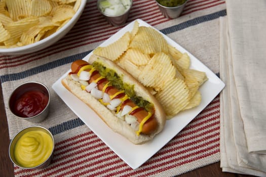 Veggie hot dog topped with mustard, ketchup, onions and relish, served with potato crisps (chips).