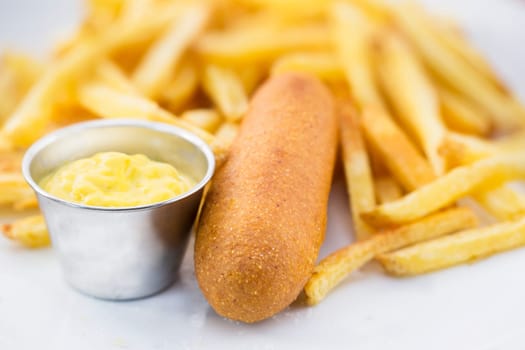 Corn dog with fries and mustard