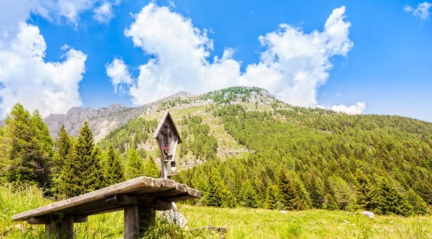 Mountain panorama with table and benches for resting and crucified. Julian Alps Friuli, Italy