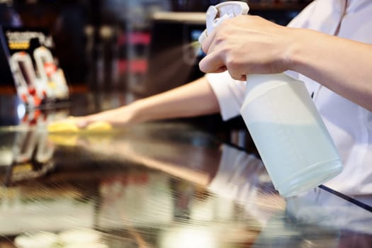 Maid service cleaning glass table with chemicals spray and rag