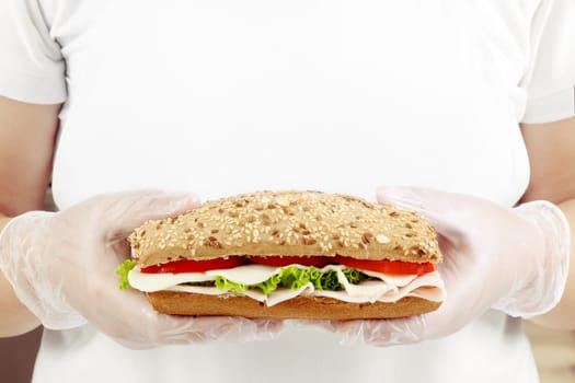Chef in white dress holding a fresh sandwich in hands