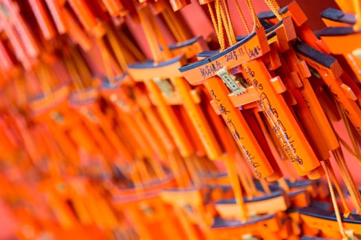 Prayers writen on small red wooden Tori Gates at Fushimi Inari Shrine in Kyoto, Japan. Selective focus on traditional japanese writing.