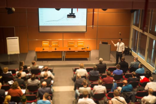 Speaker giving a talk in conference hall at business event. Audience at the conference hall. Business and Entrepreneurship. Tilt shift blur efect.
