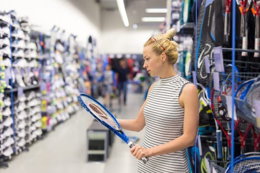 Beautiful caucasian woman shopping sports equipment in sportswear store.