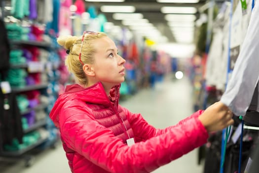 Beautiful caucasian woman shopping sportswear in sports store.