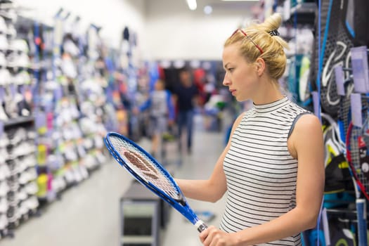 Beautiful caucasian woman shopping sports equipment in sportswear store.