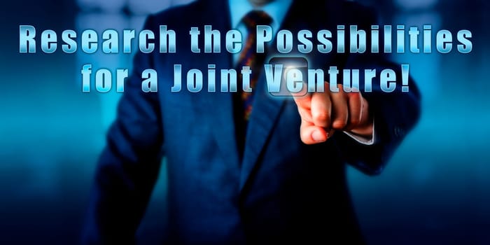Enterprise manager is pressing Research the Possibilities for a Joint Venture! on a touch screen. Business objectives metaphor, entrepreneurial spirit metaphor and call to action.