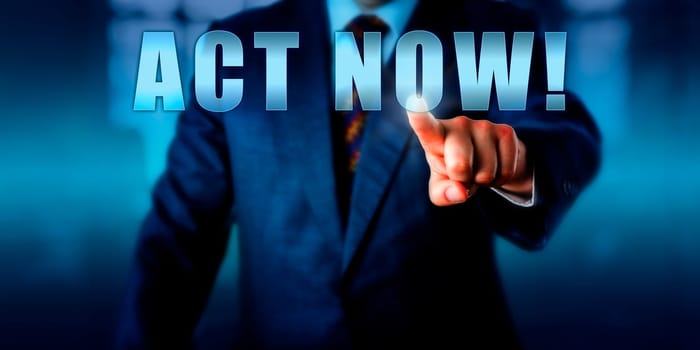 Male entrepreneur is pushing ACT NOW! on a virtual touch screen interface. Business concept and call to action with a sense of urgency, immediacy, almost emergency.