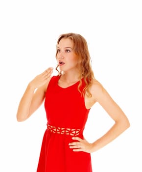 A beautiful blond young woman holding her hand for her mouth, she.is surprised what she sea's, isolated for white background..