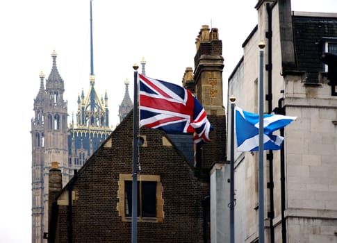 London,United Kingdom – November 27,2014: The British and Scottish flags fly in front of parts of the Westminster Palace with the Victoria Tower in the background on November 27,2014 in London.