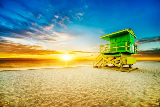 Miami South Beach sunrise with lifeguard tower and coastline with colorful cloud and blue sky.