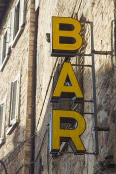 Old historical building with yellow sign Bar. Vertically.