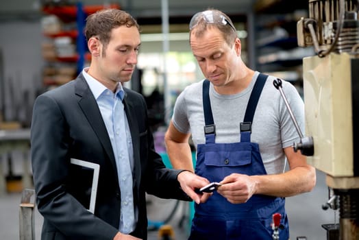 in the factory- young boss and worker in conversation