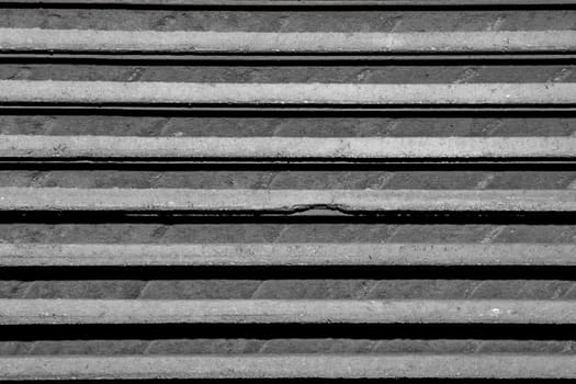 Abstract close up photo of roof tiles stacked one on top of the other. Only horziontal lines of gray are visible.