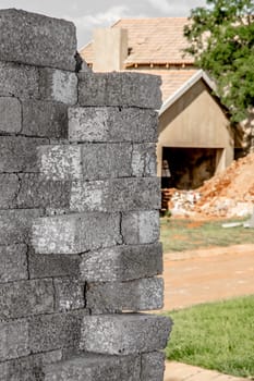 Building material stacked next to the imcomplete house that it is intended for.