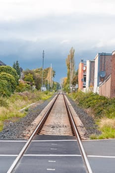 Endless-looking railway tracks in a stoic scene with a beautiful cloud image.