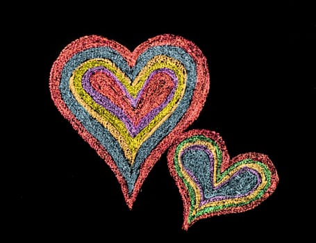 Conceptual image of love, with two vivid color shape hearts close one to each other .Vintage hand drawing on blackboard, isolated on black background, love concept, copy space available
