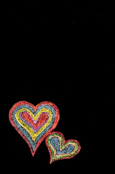 Conceptual image of love, with two vivid color shape hearts close one to each other .Vintage hand drawing on blackboard, isolated on black background, love concept, copy space available