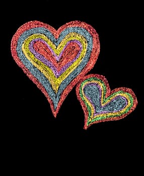 Conceptual image of love, with two vivid color shape hearts close one to each other .Vintage hand drawing on blackboard, isolated on black background, love concept, copy space available