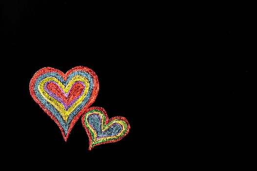 Conceptual image of love, with two vivid color shape hearts close one to each other .Vintage hand drawing on blackboard, isolated on black background, love concept, copy space available