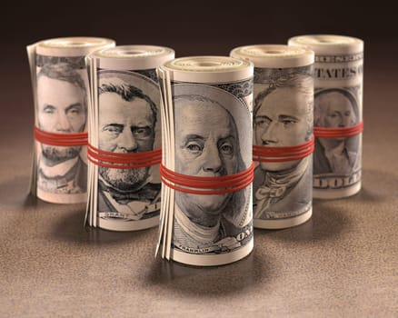 Money rolls with elastic gagging the mouths of the symbols of United States currency.