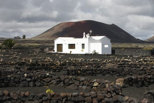 a House in the landscape of volcanic Hills on the Island of Lanzarote on the Canary Islands of Spain in the Atlantic Ocean..