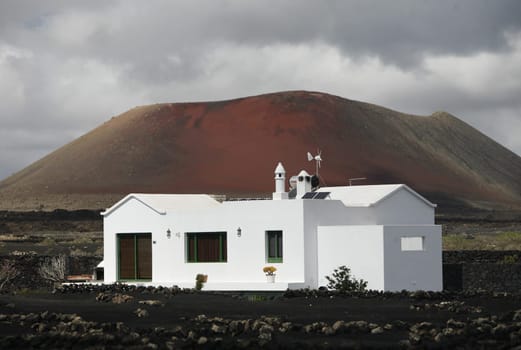 a House in the landscape of volcanic Hills on the Island of Lanzarote on the Canary Islands of Spain in the Atlantic Ocean..