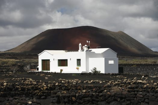 a House in the landscape of volcanic Hills on the Island of Lanzarote on the Canary Islands of Spain in the Atlantic Ocean..