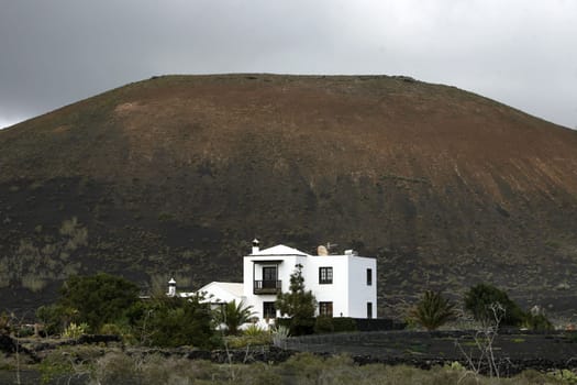 a House in the landscape of volcanic Hills on the Island of Lanzarote on the Canary Islands of Spain in the Atlantic Ocean..