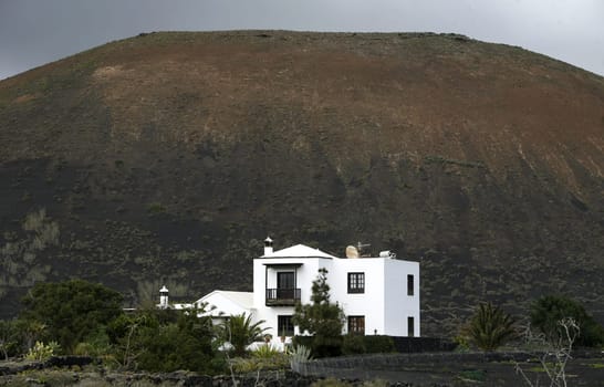 a House in the landscape of volcanic Hills on the Island of Lanzarote on the Canary Islands of Spain in the Atlantic Ocean..