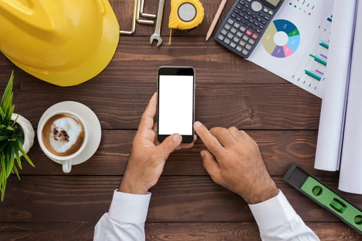 engineering using phone on his workspace top view