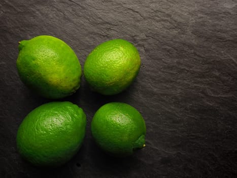 Fresh organic lime fruits on a dark slate background, healthy food background with space for text