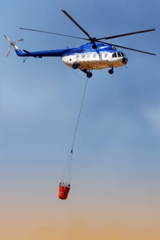 Blue fire rescue helicopter, with water bucket transportation