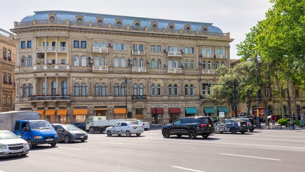 Baku, Azerbaijan - May 10, 2024: A bustling street is lined with historic buildings, complemented by luxury shops such as Bvlgari. The vibrant atmosphere is enhanced by the presence of lush greenery