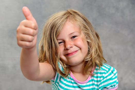 funny girl with thumb up in front of gray background