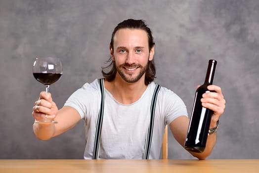 young man in front of gray background drinking red wine