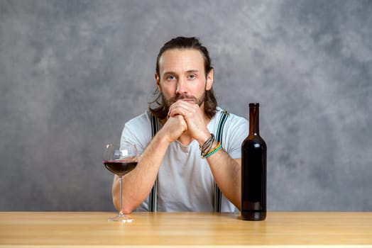 young man in front of gray background drinking red wine