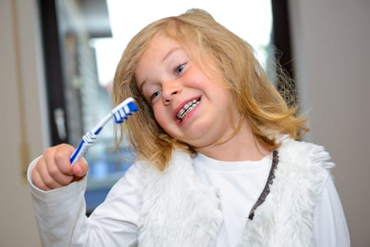 little funny girl with retainer and toothbrush looking in to the camera