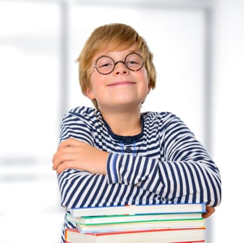 blond boy with round glasses on a pile of books