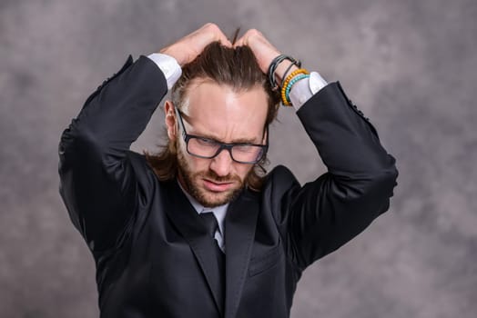 portrait of a young stressed business man in black suit