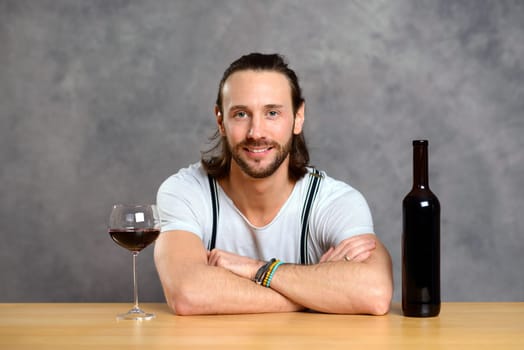young man in front of gray background drinking red wine