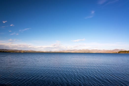 Landscape view of Yellowstone Lake with deep blue water a hills in the background in Yellowstone National Park