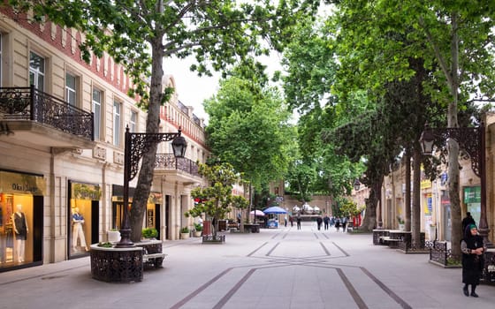 Ganja, Azerbaijan - May 13, 2024: People stroll along Javad Khan Street in Ganja, Azerbaijan, enjoying the vibrant afternoon with greenery and local shops. The lively street adds to the city's charm