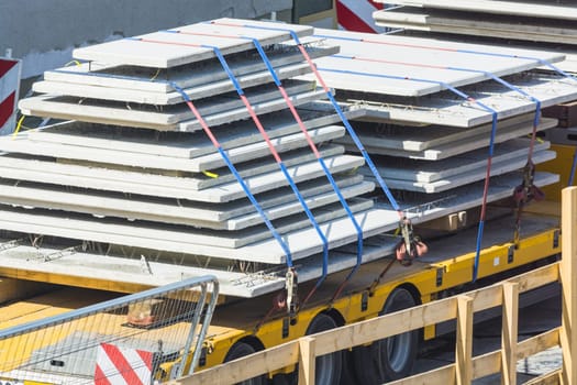 Large truck with flatbed trailer towing loaded with building prefabricated walls..
